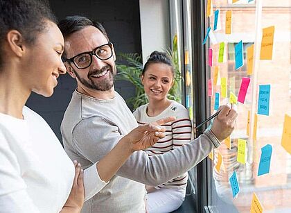 Agile Teamarbeit: Kollegen arbeiten mit Post-It Notes am Fenster