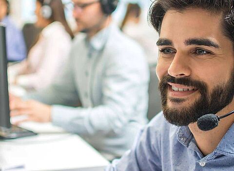Kundenzentrierung im Callcenter: freundlicher Berater mit Headset - Customer Centricity