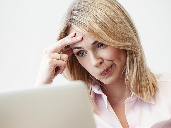 Nachdenke Frau vor ihrem Laptop