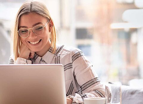 Frau mit Brille sitzt vor dem Laptop