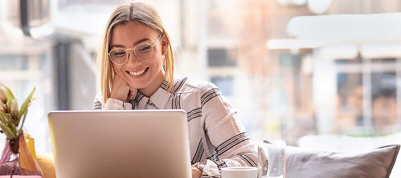 Frau mit Brille sitzt vor dem Laptop