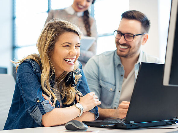 Zwei Personen mit Freude bei der Arbeit vor dem Laptop